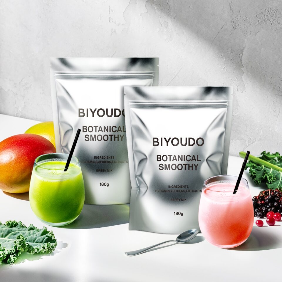 ビヨウドウ BOTANICAL SMOOTHY_銀色のパウチが2つ並び、緑とピンクのスムージーのグラス、マンゴーやケール、ベリーが添えられた写真